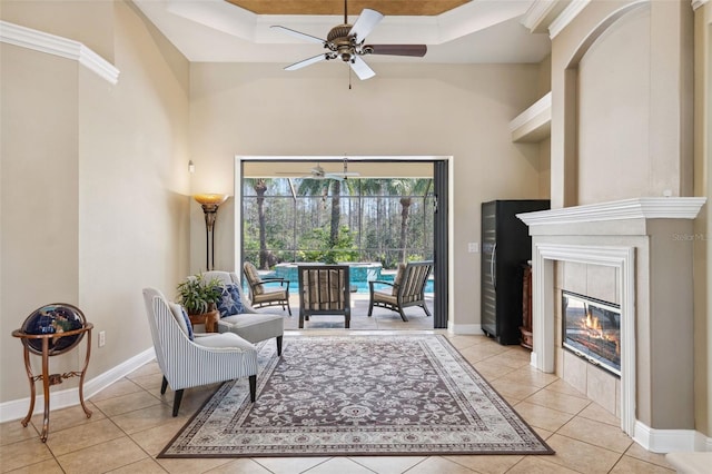 sitting room with light tile patterned floors, a fireplace, a raised ceiling, and ceiling fan