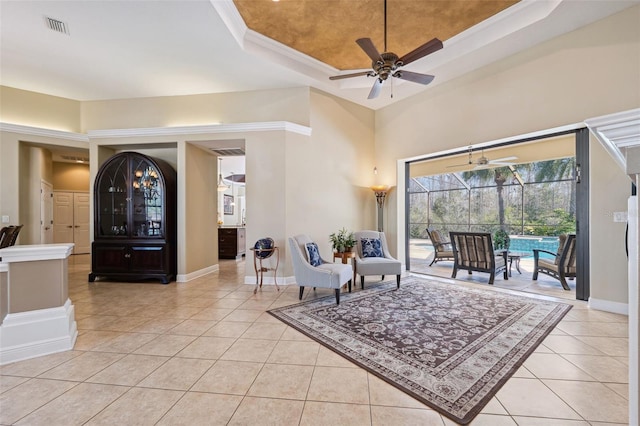 living room with light tile patterned floors, ceiling fan, and a tray ceiling