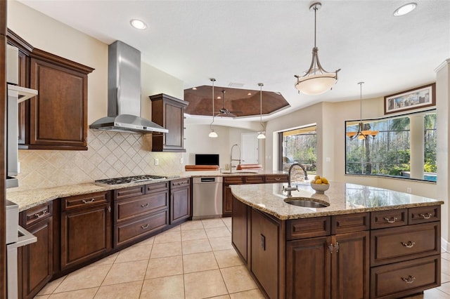 kitchen with wall chimney range hood, sink, hanging light fixtures, and appliances with stainless steel finishes