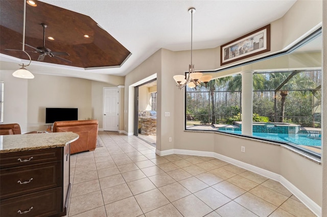 kitchen featuring light tile patterned flooring, dark brown cabinets, pendant lighting, light stone countertops, and ceiling fan with notable chandelier