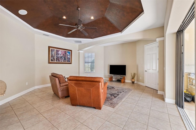 tiled living room with a raised ceiling and ceiling fan