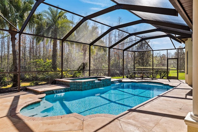 view of pool with an in ground hot tub, pool water feature, glass enclosure, and a patio area