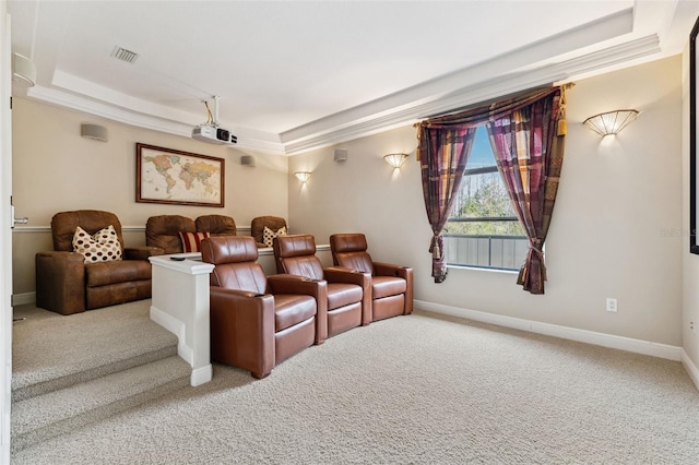 carpeted home theater room with a tray ceiling and ornamental molding