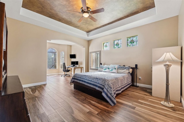 bedroom featuring a tray ceiling, ceiling fan, and hardwood / wood-style flooring