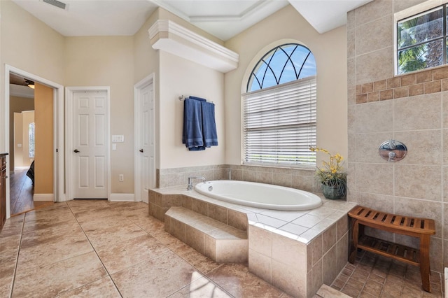 bathroom with a relaxing tiled tub and tile patterned floors