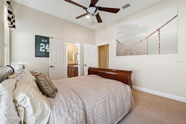 bedroom featuring ceiling fan, light colored carpet, and ensuite bath