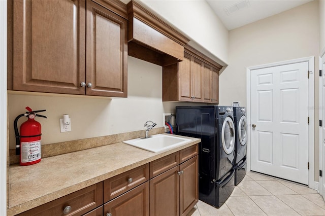 laundry room featuring light tile patterned flooring, cabinets, sink, and washer and dryer