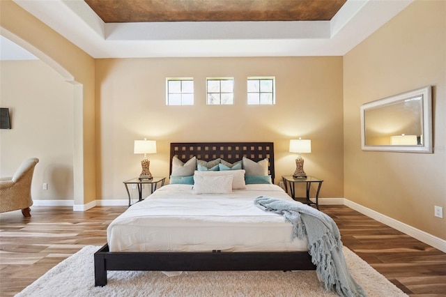 20200 Lace Cascade Rd, Land O Lakes, FL 34637 - bedroom with wood finished floors, arched walkways, a tray ceiling, and baseboards