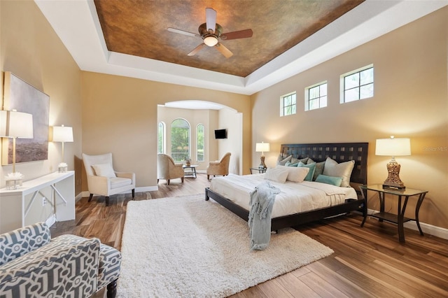 20200 Lace Cascade Rd, Land O Lakes, FL 34637 - bedroom featuring a tray ceiling, baseboards, wood finished floors, arched walkways, and a ceiling fan
