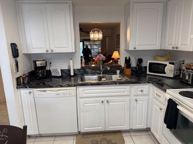 kitchen featuring light tile patterned flooring, sink, white cabinets, white appliances, and an inviting chandelier