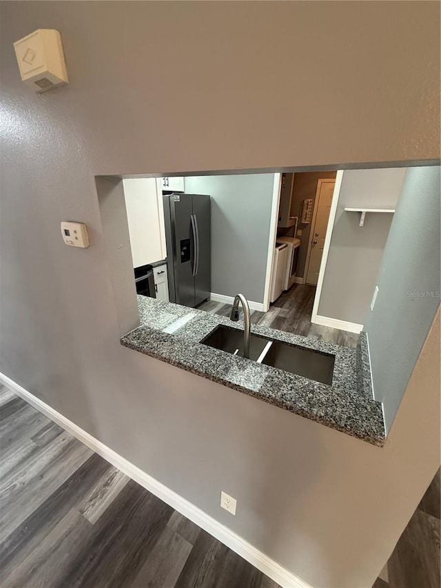 kitchen featuring white cabinetry, stainless steel fridge, sink, and dark stone countertops