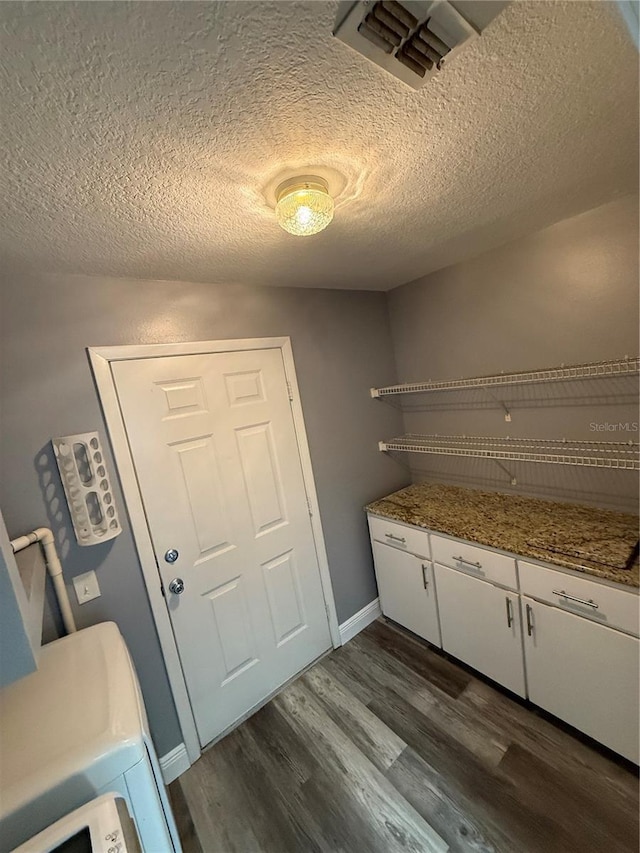 washroom with cabinets, washer / dryer, dark hardwood / wood-style floors, and a textured ceiling