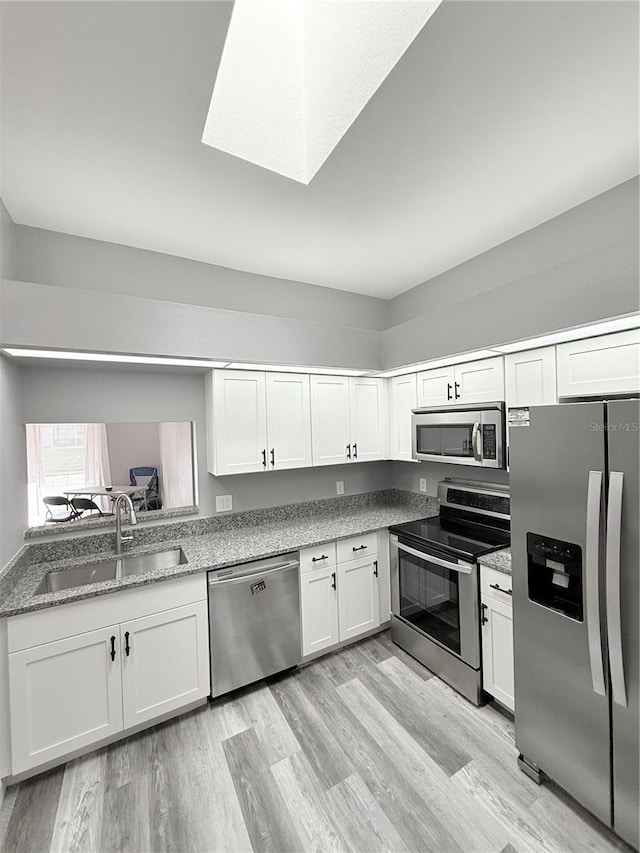 4218 San Rafael Ave, New Port Richey, FL 34655 - kitchen with white cabinetry, a sink, light wood-type flooring, and appliances with stainless steel finishes