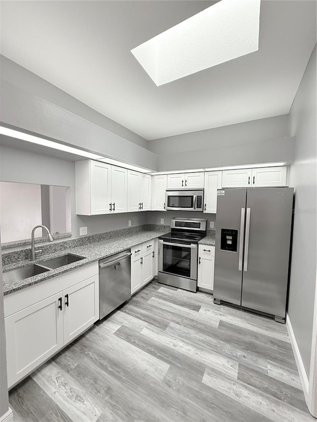 4218 San Rafael Ave, New Port Richey, FL 34655 - kitchen with white cabinetry, light wood-type flooring, stainless steel appliances, a sink, and a skylight