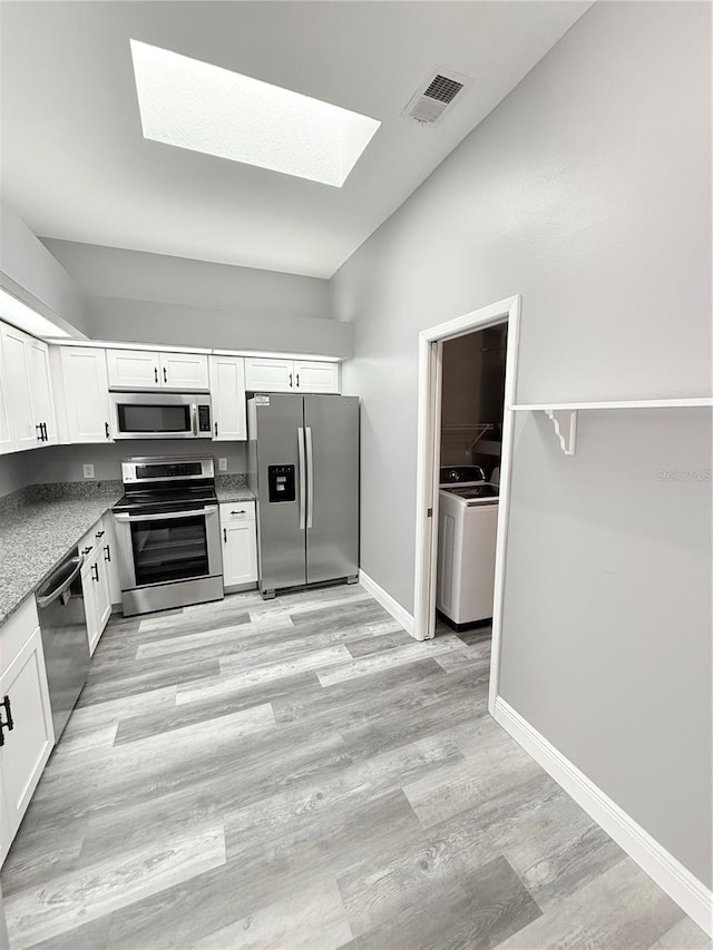 4218 San Rafael Ave, New Port Richey, FL 34655 - kitchen with visible vents, vaulted ceiling with skylight, appliances with stainless steel finishes, white cabinetry, and light wood-style floors