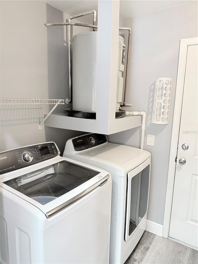 4218 San Rafael Ave, New Port Richey, FL 34655 - laundry area featuring light wood finished floors, washing machine and clothes dryer, a textured ceiling, laundry area, and baseboards