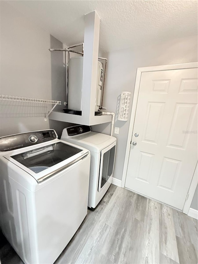 4218 San Rafael Ave, New Port Richey, FL 34655 - washroom featuring washing machine and clothes dryer, a textured ceiling, baseboards, laundry area, and light wood-style floors