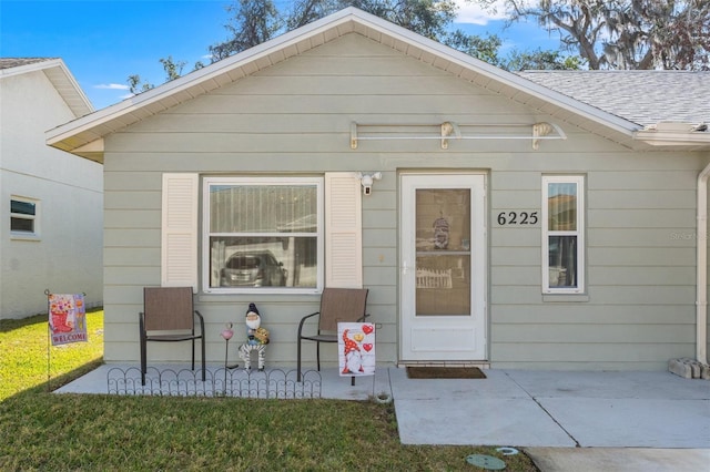 entrance to property with a patio area and a lawn