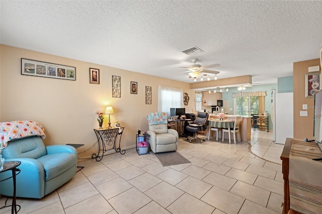 living room with light tile patterned flooring, ceiling fan, and a textured ceiling