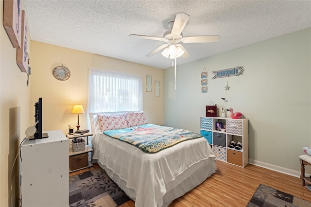 bedroom featuring ceiling fan, hardwood / wood-style floors, and a textured ceiling