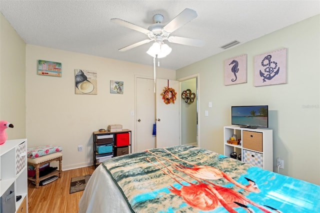 bedroom featuring ceiling fan, a textured ceiling, and light wood-type flooring