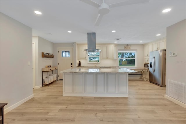 kitchen featuring a center island, light stone counters, appliances with stainless steel finishes, and island exhaust hood