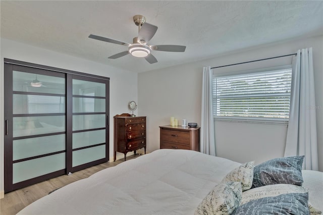 bedroom featuring ceiling fan, light hardwood / wood-style flooring, and a textured ceiling