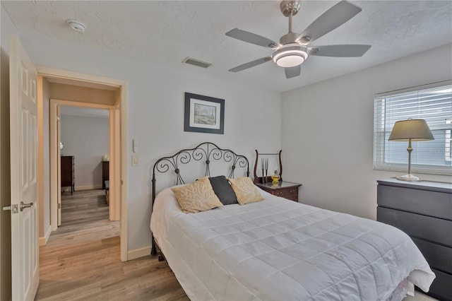 bedroom featuring ceiling fan, a textured ceiling, and light hardwood / wood-style flooring