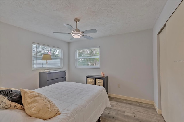 bedroom featuring ceiling fan, a textured ceiling, and light wood-type flooring