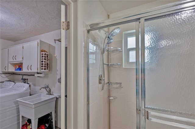 bathroom featuring walk in shower, washing machine and clothes dryer, sink, and a textured ceiling