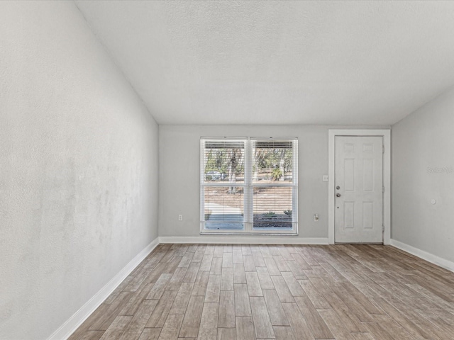 unfurnished room with light hardwood / wood-style flooring and a textured ceiling