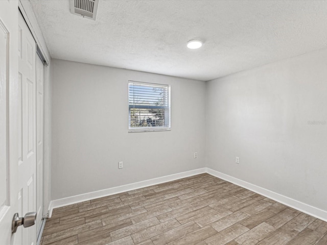 empty room with wood-type flooring and a textured ceiling