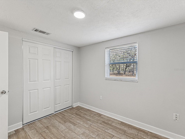 unfurnished bedroom featuring light hardwood / wood-style floors, a closet, and a textured ceiling