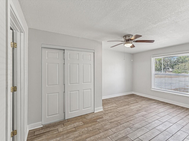 unfurnished bedroom with a textured ceiling, a closet, ceiling fan, and light wood-type flooring