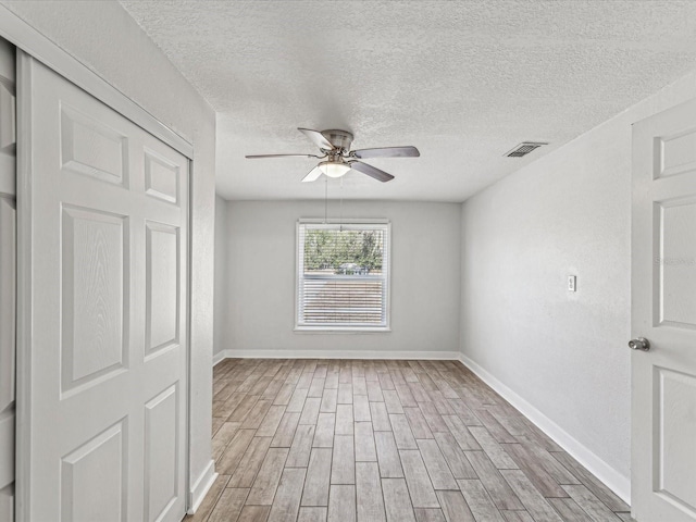 spare room featuring ceiling fan, a textured ceiling, and light hardwood / wood-style floors