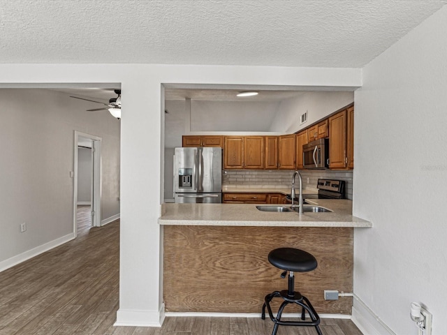 kitchen with dark wood-type flooring, sink, a kitchen breakfast bar, stainless steel appliances, and decorative backsplash