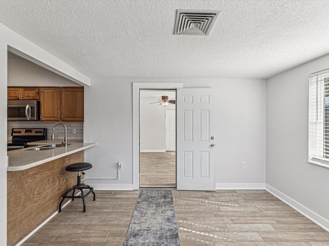 kitchen with sink, backsplash, a kitchen breakfast bar, ceiling fan, and stainless steel appliances