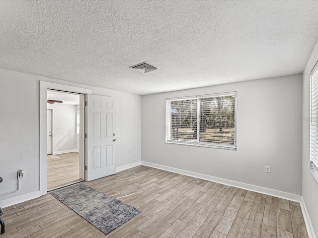 unfurnished room with light hardwood / wood-style flooring and a textured ceiling