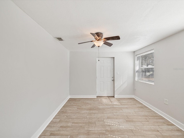 unfurnished room with ceiling fan, a textured ceiling, and light wood-type flooring