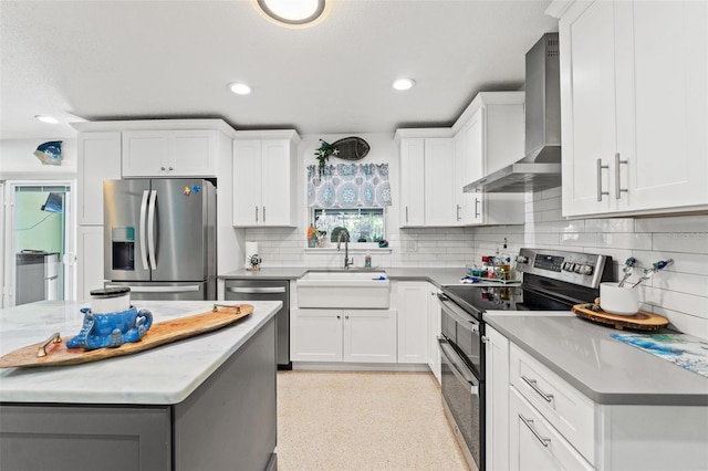 kitchen with white cabinetry, appliances with stainless steel finishes, sink, and wall chimney range hood