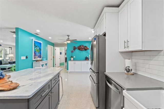 kitchen featuring appliances with stainless steel finishes, gray cabinets, light stone countertops, decorative backsplash, and white cabinets