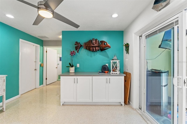 kitchen featuring ceiling fan and white cabinets