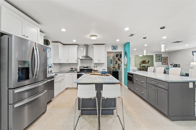 kitchen with stainless steel appliances, a center island, white cabinets, and wall chimney exhaust hood