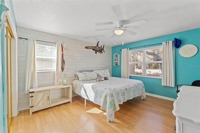 bedroom with ceiling fan, multiple windows, light hardwood / wood-style flooring, and a textured ceiling