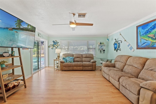 living room with crown molding, a healthy amount of sunlight, and light wood-type flooring