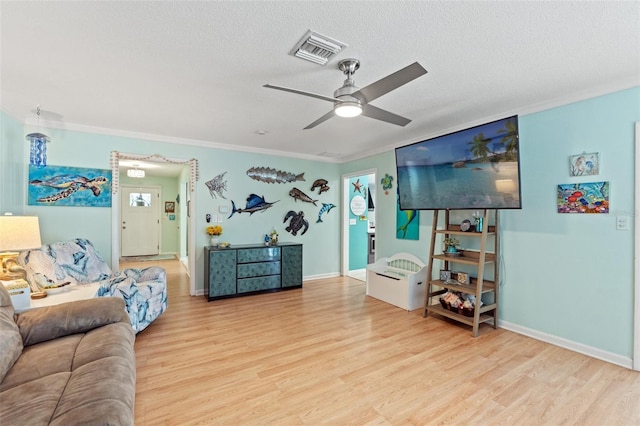 living room featuring crown molding, ceiling fan, a textured ceiling, and light wood-type flooring