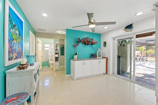 kitchen with ceiling fan, white cabinets, and a textured ceiling