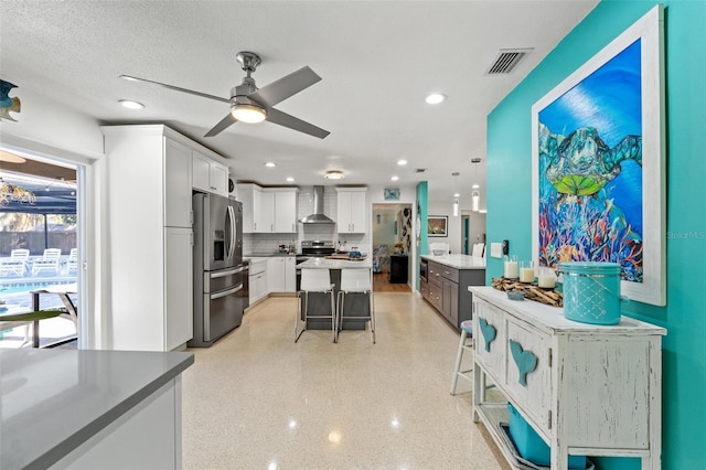 kitchen featuring appliances with stainless steel finishes, white cabinetry, a kitchen breakfast bar, a kitchen island, and decorative light fixtures