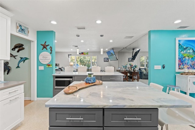 kitchen with gray cabinetry, white cabinets, and a kitchen bar