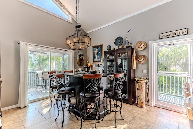 dining room with high vaulted ceiling, indoor bar, light tile patterned floors, a notable chandelier, and crown molding